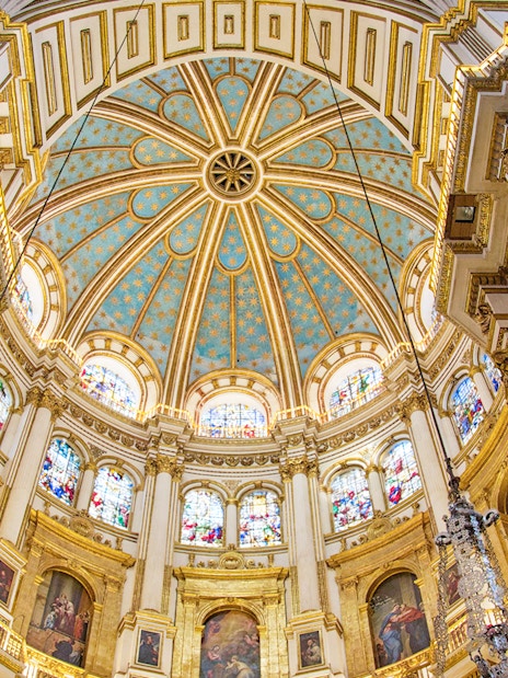 Granada Cathedral interior with ornate columns and stained glass windows.