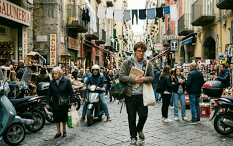 Naples street scene with people, scooters, and market stalls, part of self-guided city exploration game.