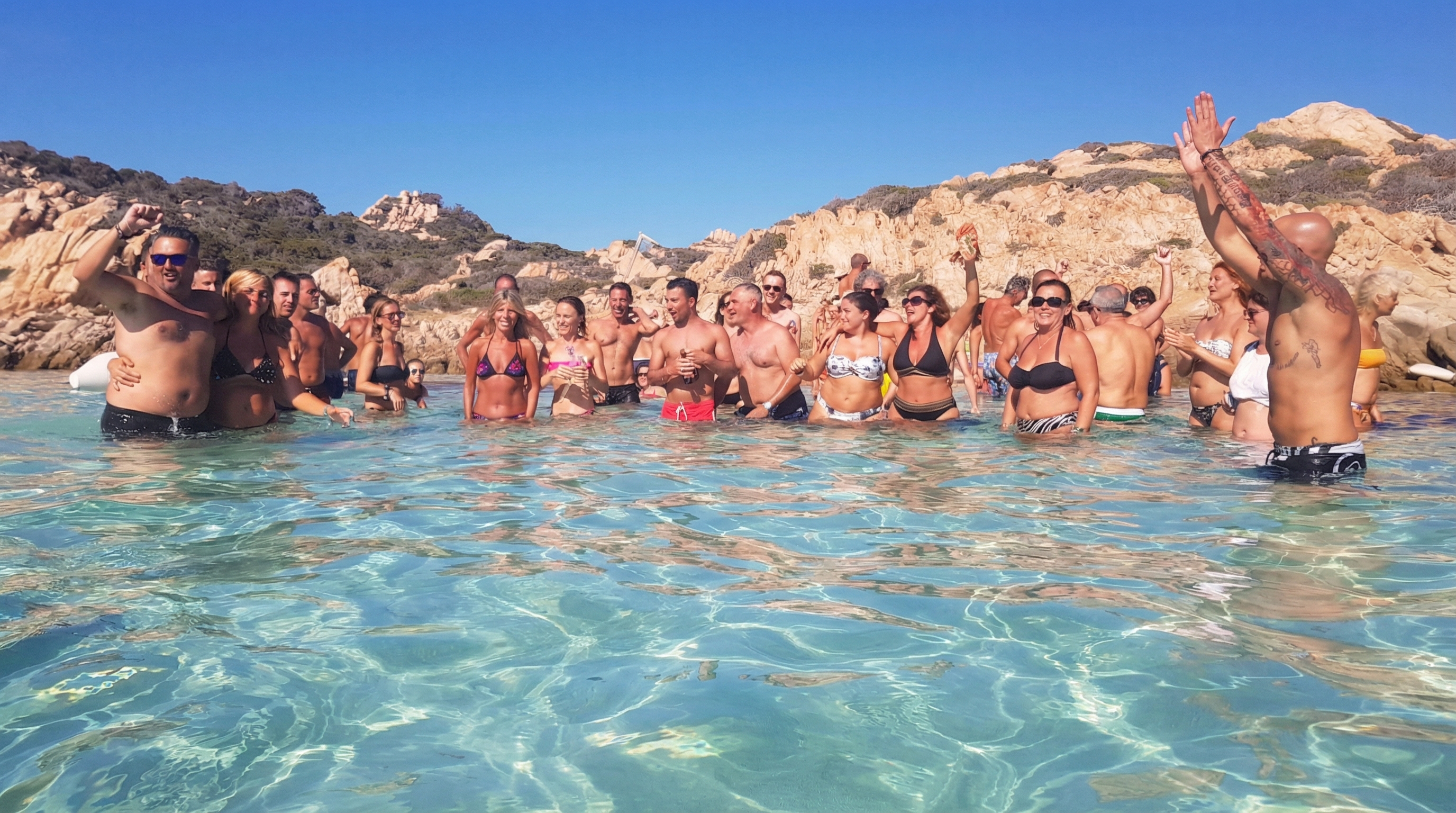 Group enjoying the water during a catamaran tour in La Maddalena, Italy.