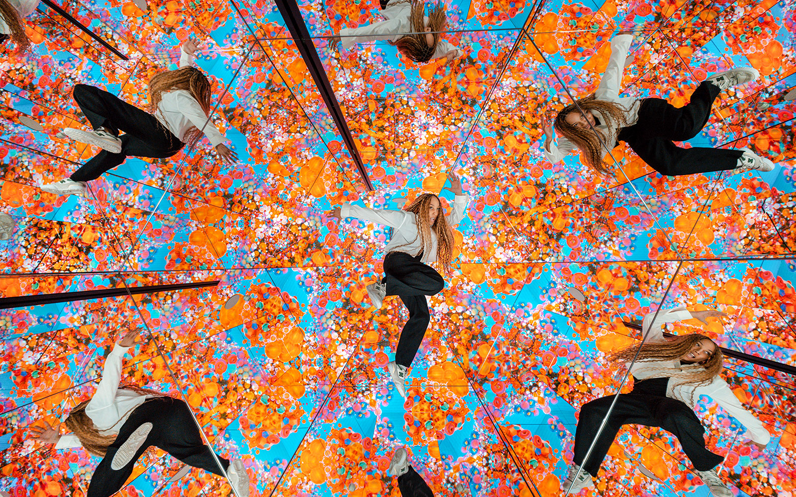 Tourist exploring mirrored room with vibrant floral patterns at House of Hype, Dubai.