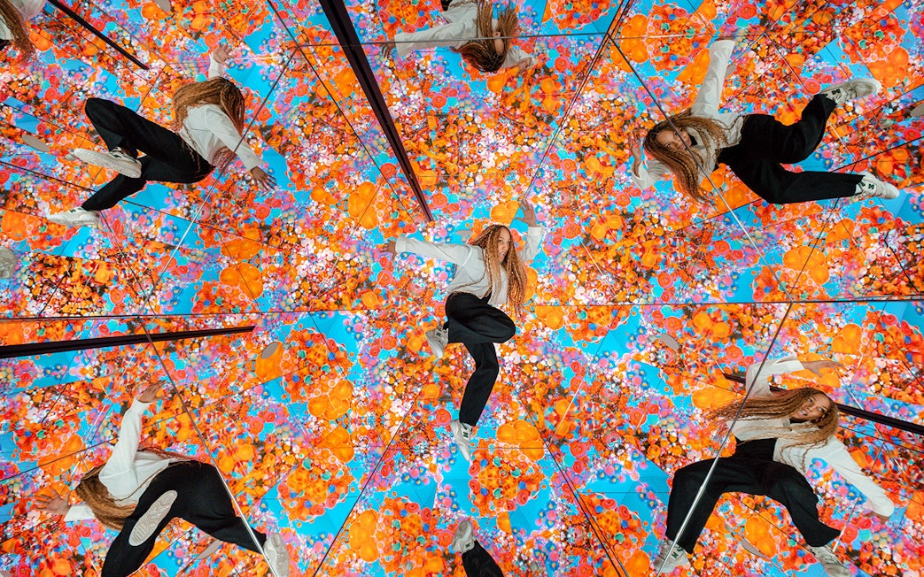Tourist exploring mirrored room with vibrant floral patterns at House of Hype, Dubai.