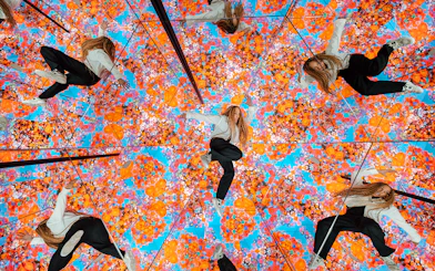 Tourist exploring mirrored room with vibrant floral patterns at House of Hype, Dubai.