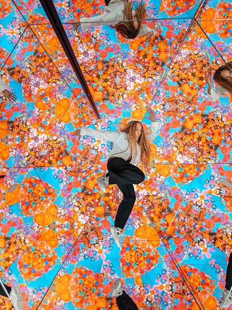 Tourist exploring mirrored room with vibrant floral patterns at House of Hype, Dubai.