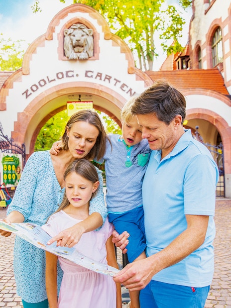 Family exploring map at Zoo Leipzig entrance.