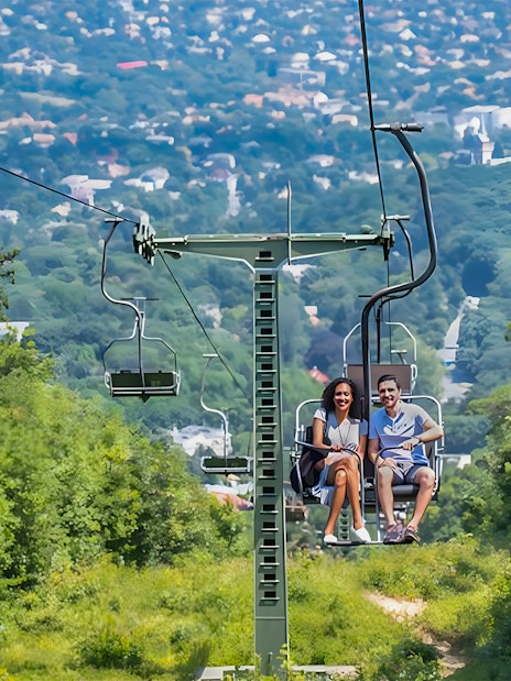 Gondola lift with passengers overlooking Budapest cityscape.