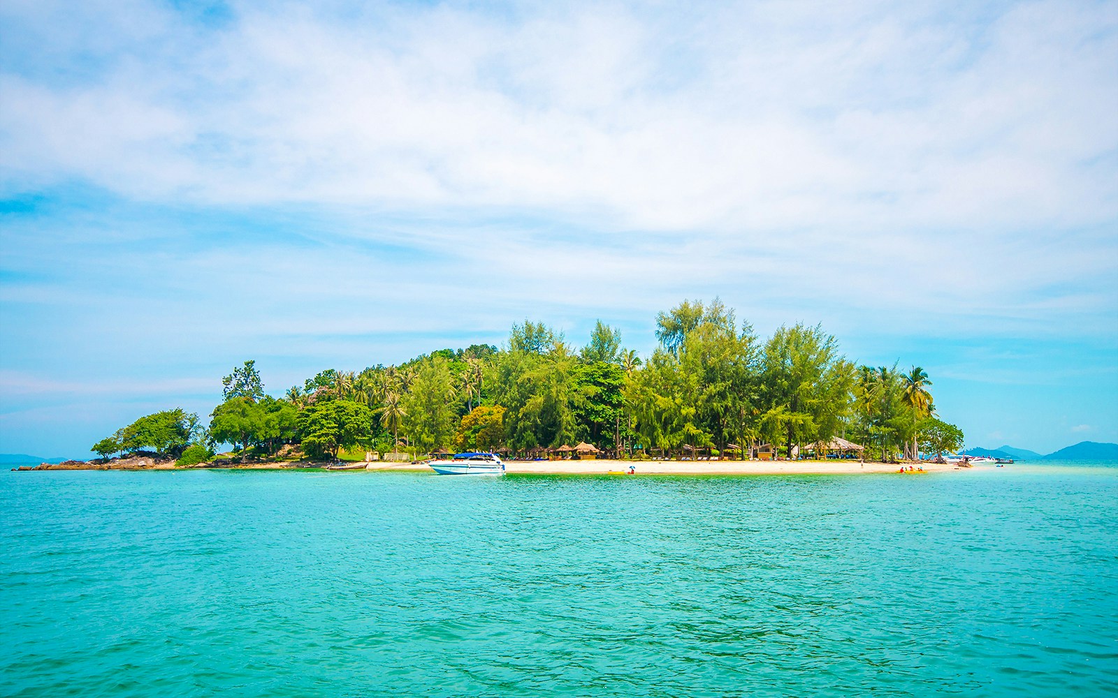 Tourists kayaking near the sandy shores of Naka Noi Island, Thailand, with lush greenery in the background.