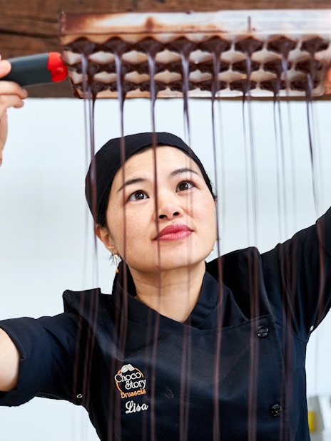 Chocolatier pouring chocolate into molds at Choco Story Brussels.