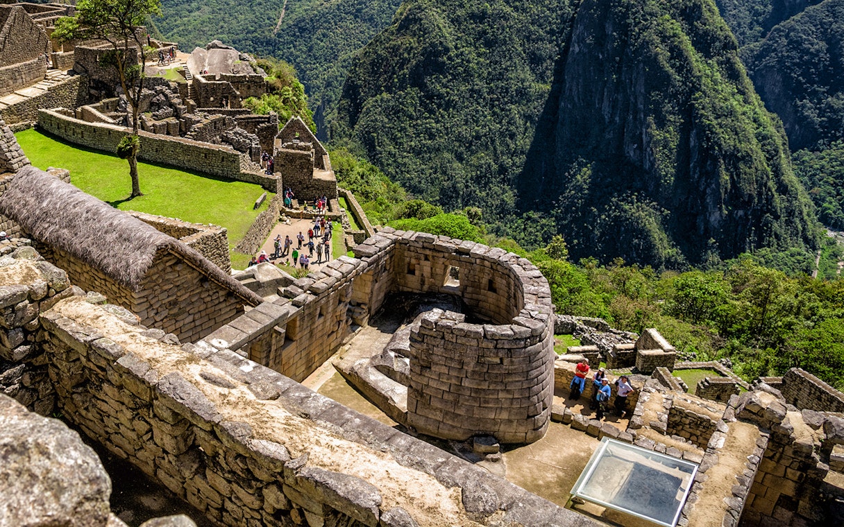 Sun Temple at Machu Picchu with surrounding stone structures and lush mountain backdrop.
