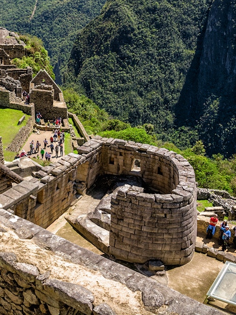 Sun Temple at Machu Picchu with surrounding stone structures and lush mountain backdrop.