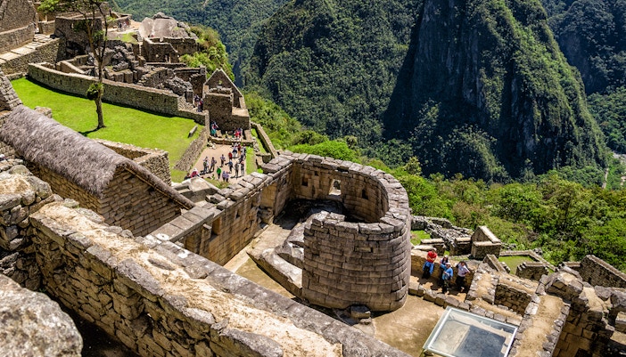 Sun Temple at Machu Picchu with surrounding stone structures and lush mountain backdrop.