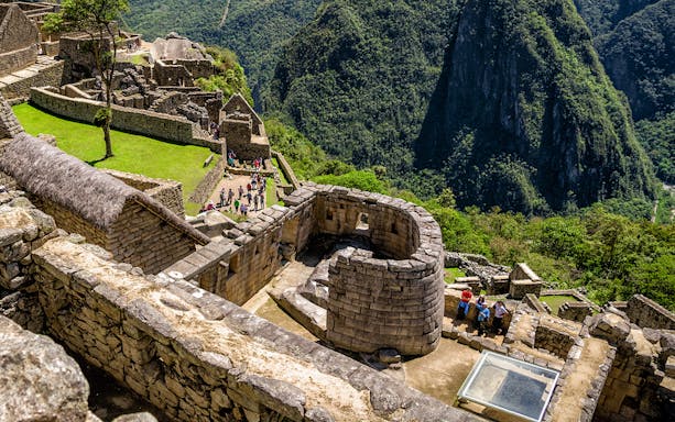 Sun Temple at Machu Picchu with surrounding stone structures and lush mountain backdrop.