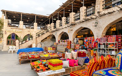 Souq Waqif market stalls with colorful textiles and traditional goods, Doha, Qatar.