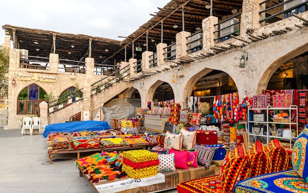 Souq Waqif market stalls with colorful textiles and traditional goods, Doha, Qatar.