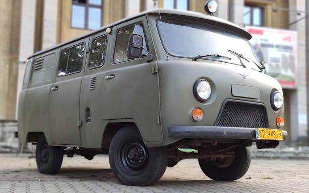 Retro car used for Nowa Huta guided tour in Kraków, parked in front of a building.