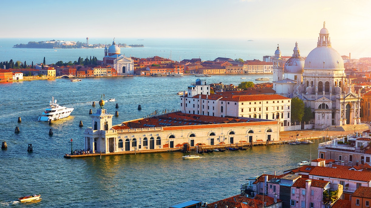 Top view at Cathedral of Santa Maria della Salute in district Dorsoduro and island Giudecca. Evening sunset yachts on sea water.