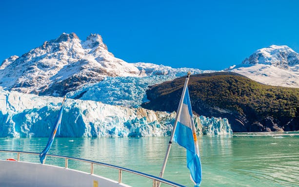 Boat approaching Spegazzini Glacier with snow-capped mountains in Los Glaciares National Park, Argentina.