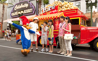 Visitors meeting a character at Universal Studios Singapore near a popcorn stand.
