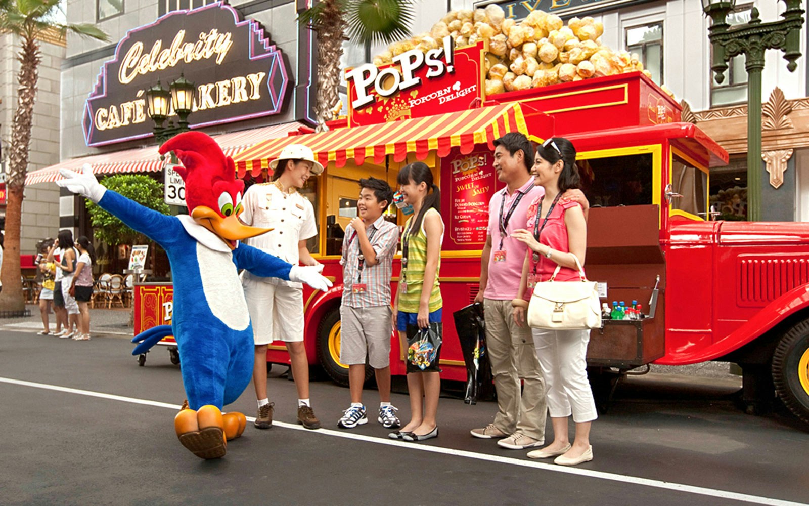 Visitors meeting a character at Universal Studios Singapore near a popcorn stand.