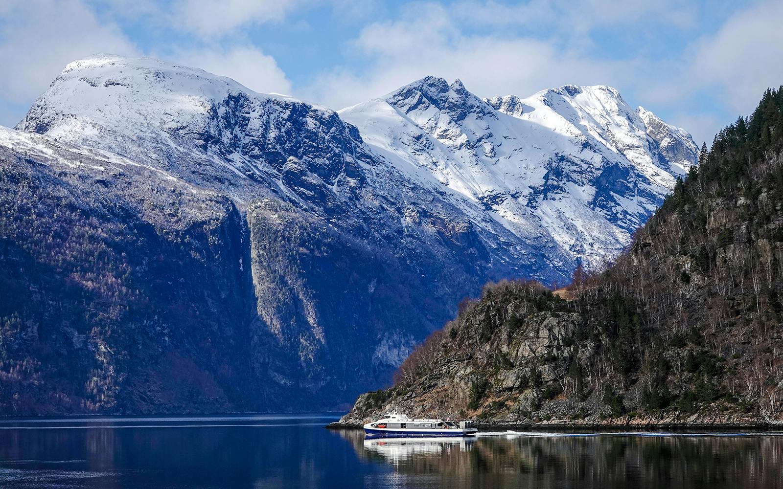 Cruise ship on Silent Fjord in Alesund, Norway with snow-capped mountains.