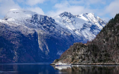 Cruise ship on Silent Fjord in Alesund, Norway with snow-capped mountains.
