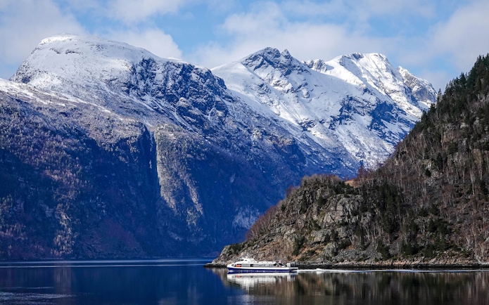 Cruise ship on Silent Fjord in Alesund, Norway with snow-capped mountains.