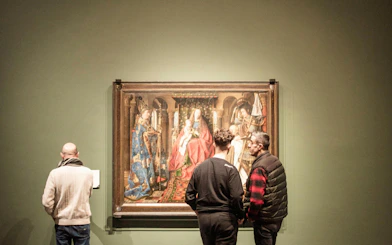 Visitors viewing a historic painting at Groeningemuseum, Bruges.
