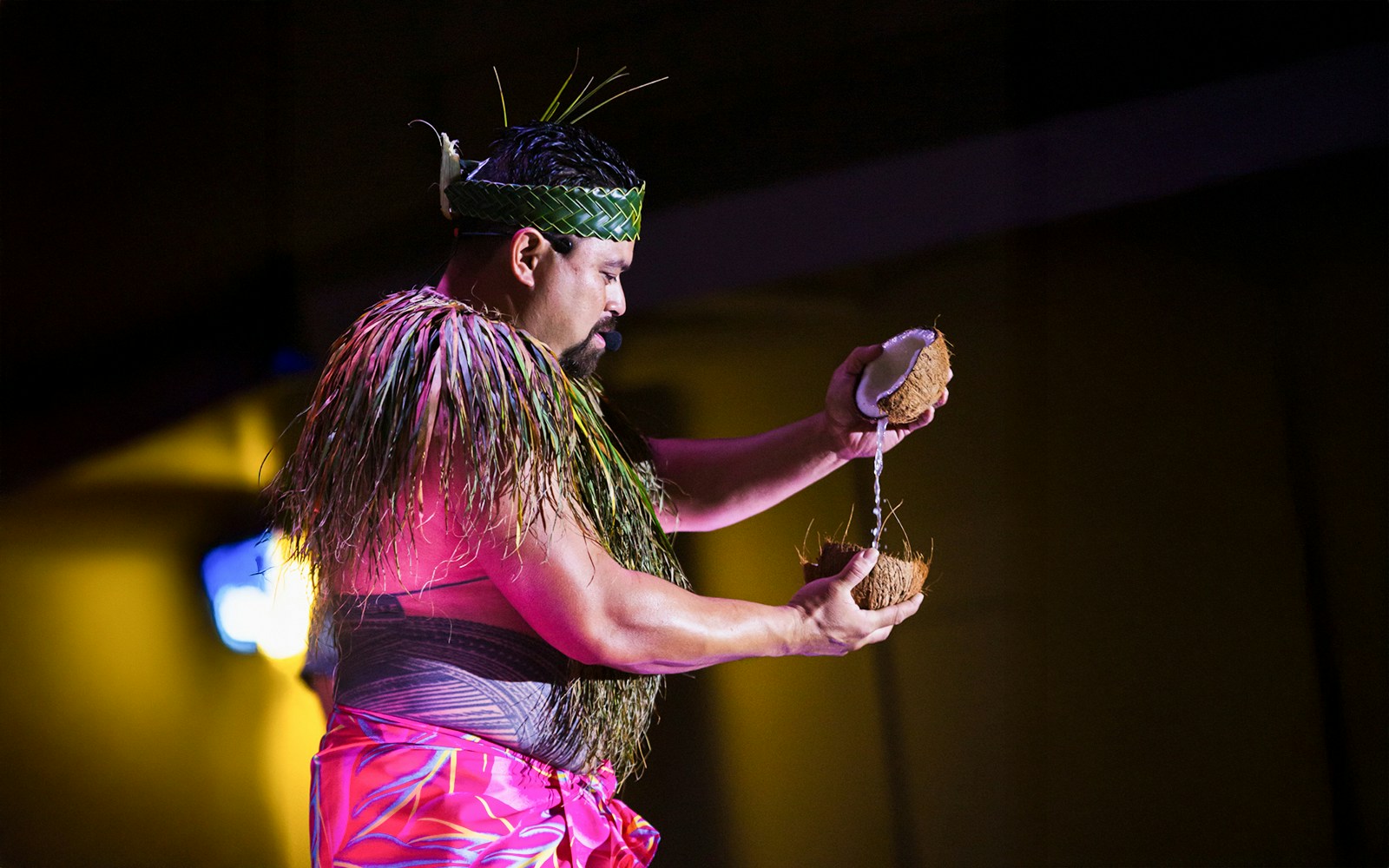 Performer at Moana Luau in Hawaii pouring coconut water during traditional Hawaiian ceremony.