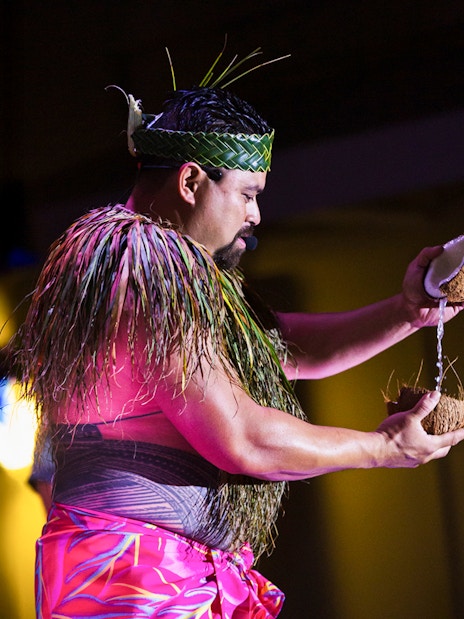 Performer at Moana Luau in Hawaii pouring coconut water during traditional Hawaiian ceremony.