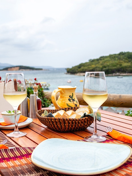 Dining setup with wine overlooking the sea in Saranda, Albania.