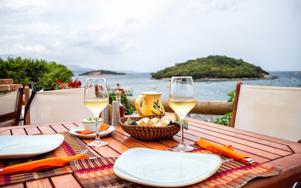 Dining setup with wine overlooking the sea in Saranda, Albania.