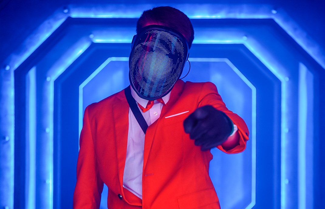 Masked performer in neon-lit corridor at Halloween event, Thorpe Park.