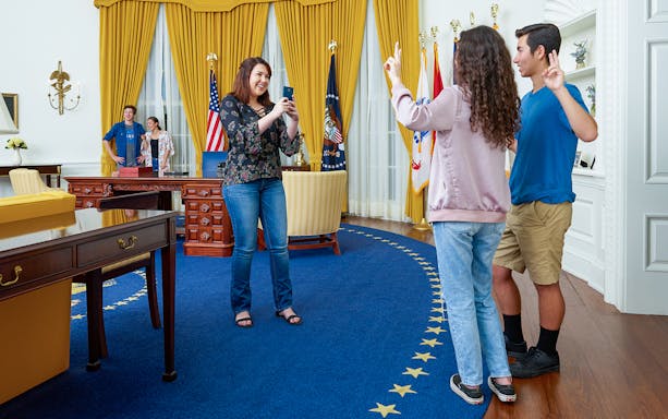 Visitors posing for photos in a replica of Nixon’s Oval Office with presidential decor.