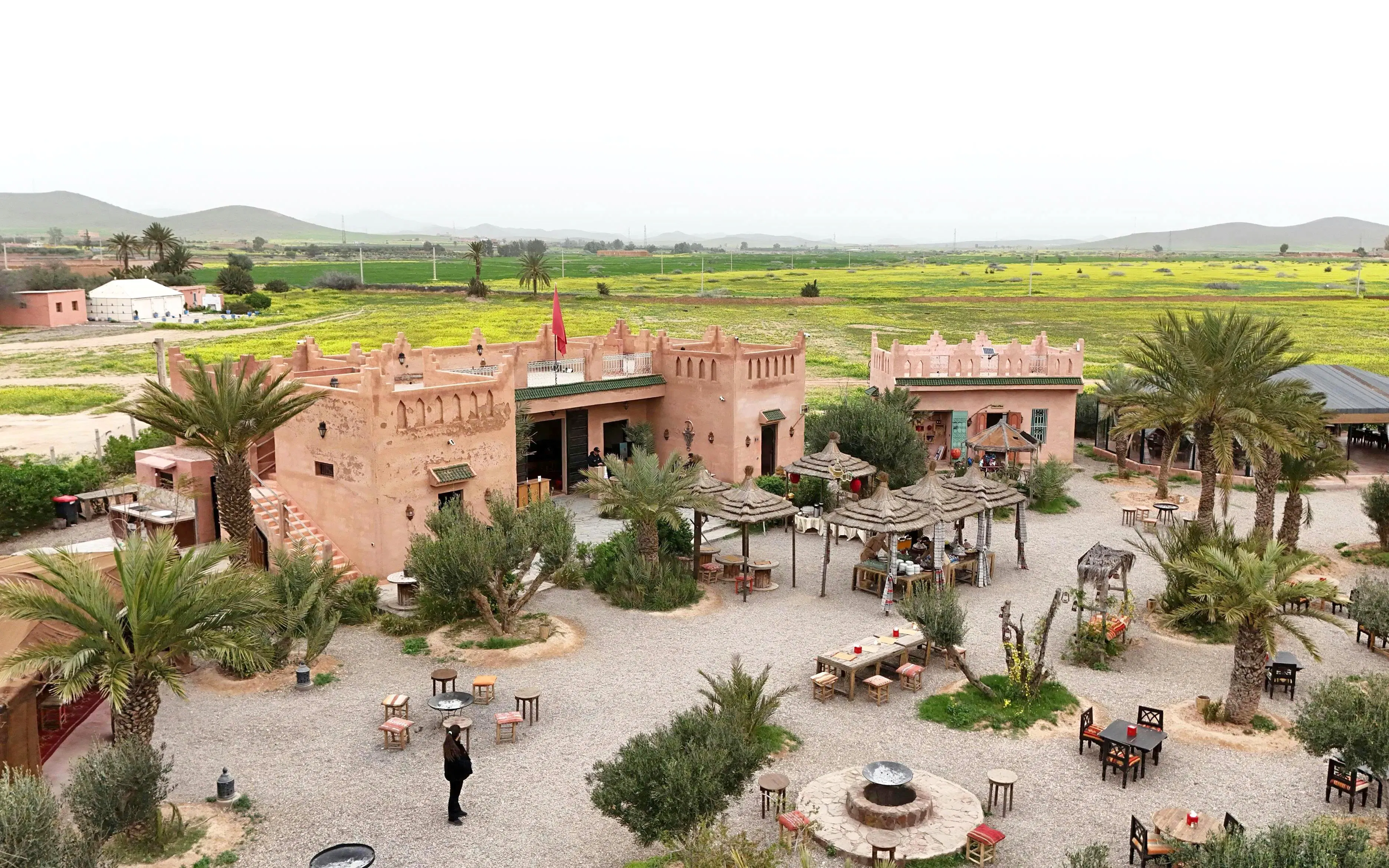 Berber village courtyard with traditional architecture near Marrakesh, surrounded by green fields.