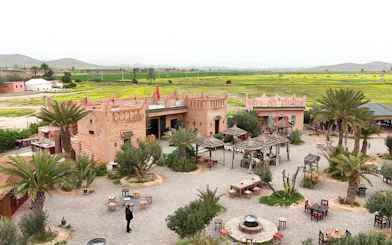 Berber village courtyard with traditional architecture near Marrakesh, surrounded by green fields.