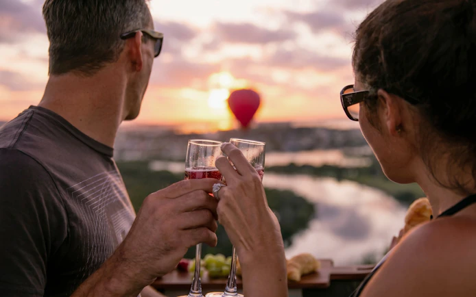 Couple toasting with champagne in hot air balloon over Gold Coast at sunset.