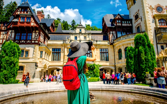 Tourist taking photo at Peles Castle courtyard, Romania.