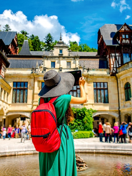 Tourist taking photo at Peles Castle courtyard, Romania.