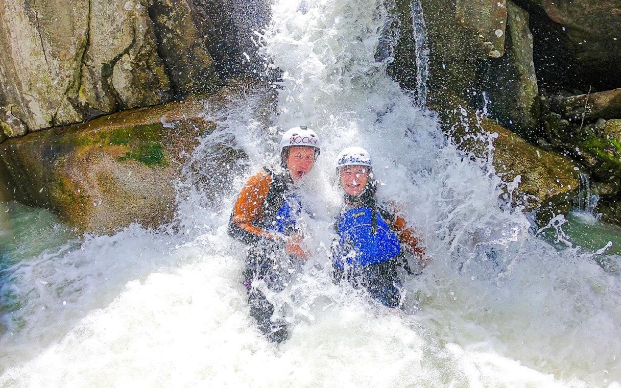 Adventurers enjoying canyoning under a waterfall in Interlaken.