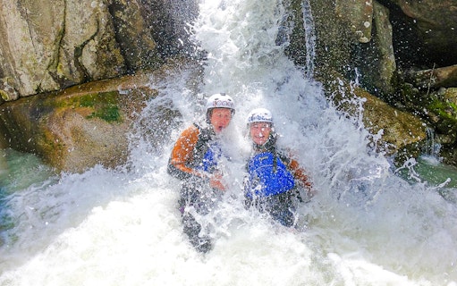 Adventurers enjoying canyoning under a waterfall in Interlaken.