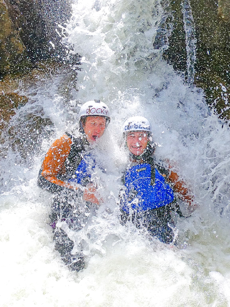 Adventurers enjoying canyoning under a waterfall in Interlaken.