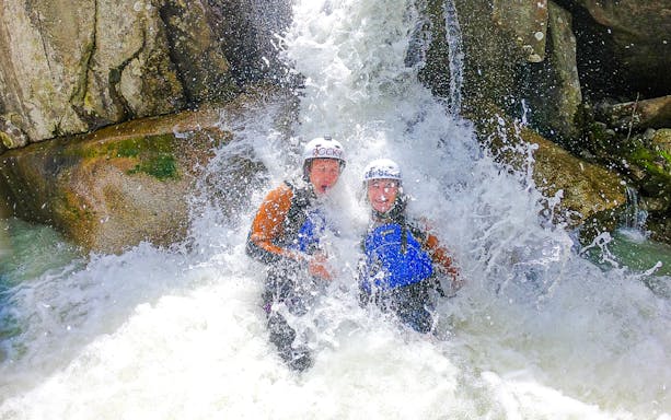 Adventurers enjoying canyoning under a waterfall in Interlaken.