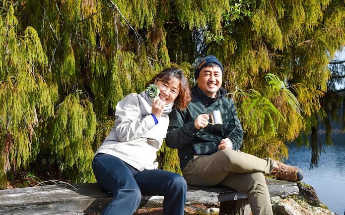 Tourists enjoying a break during a rainforest walk at Franz Josef, surrounded by lush greenery.