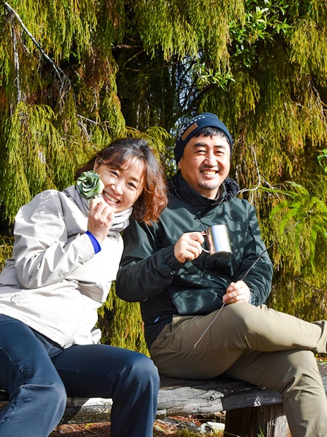 Tourists enjoying a break during a rainforest walk at Franz Josef, surrounded by lush greenery.