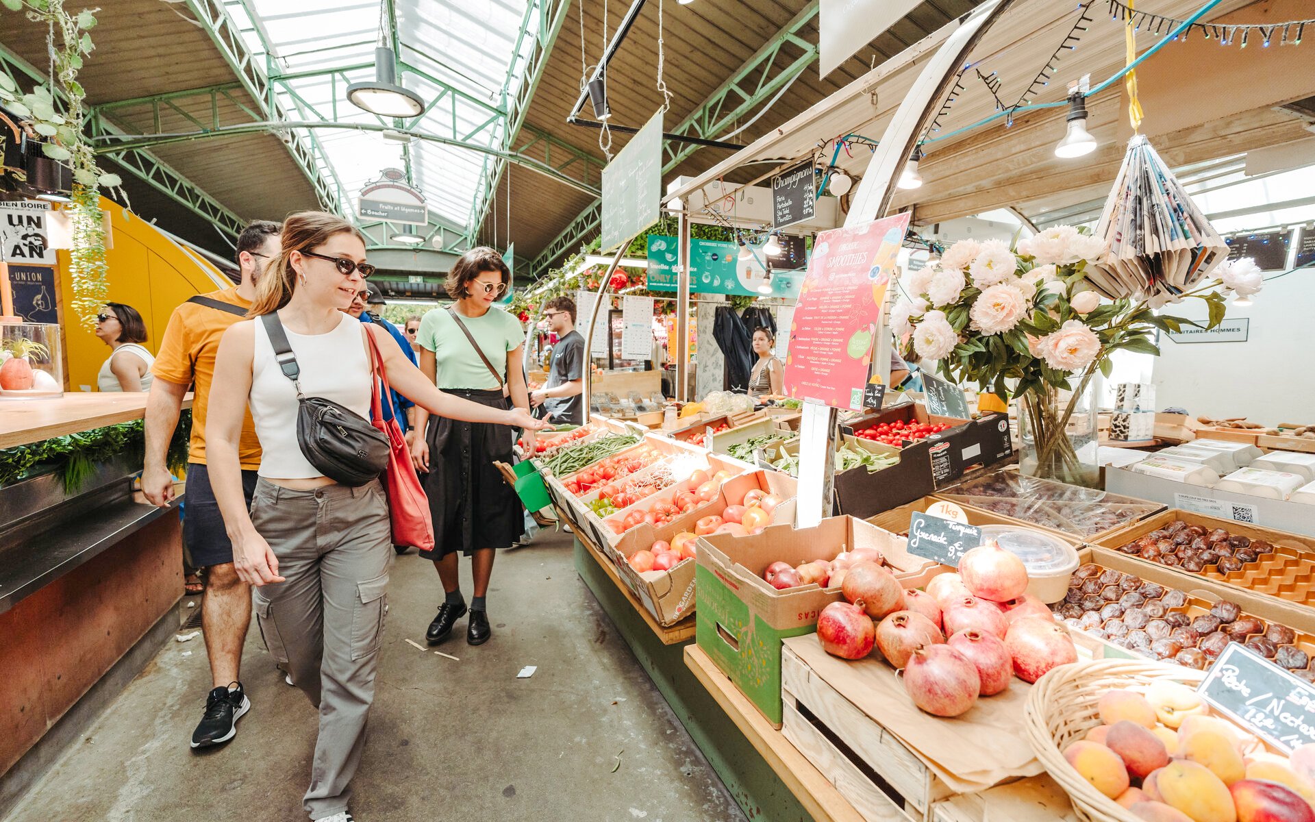 Visitors exploring a vibrant Parisian market with fresh produce on the Ultimate Paris Food Tour.