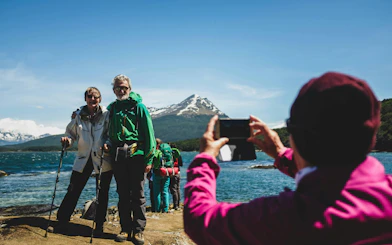 Hikers posing by a lake with mountains in Tierra del Fuego National Park.