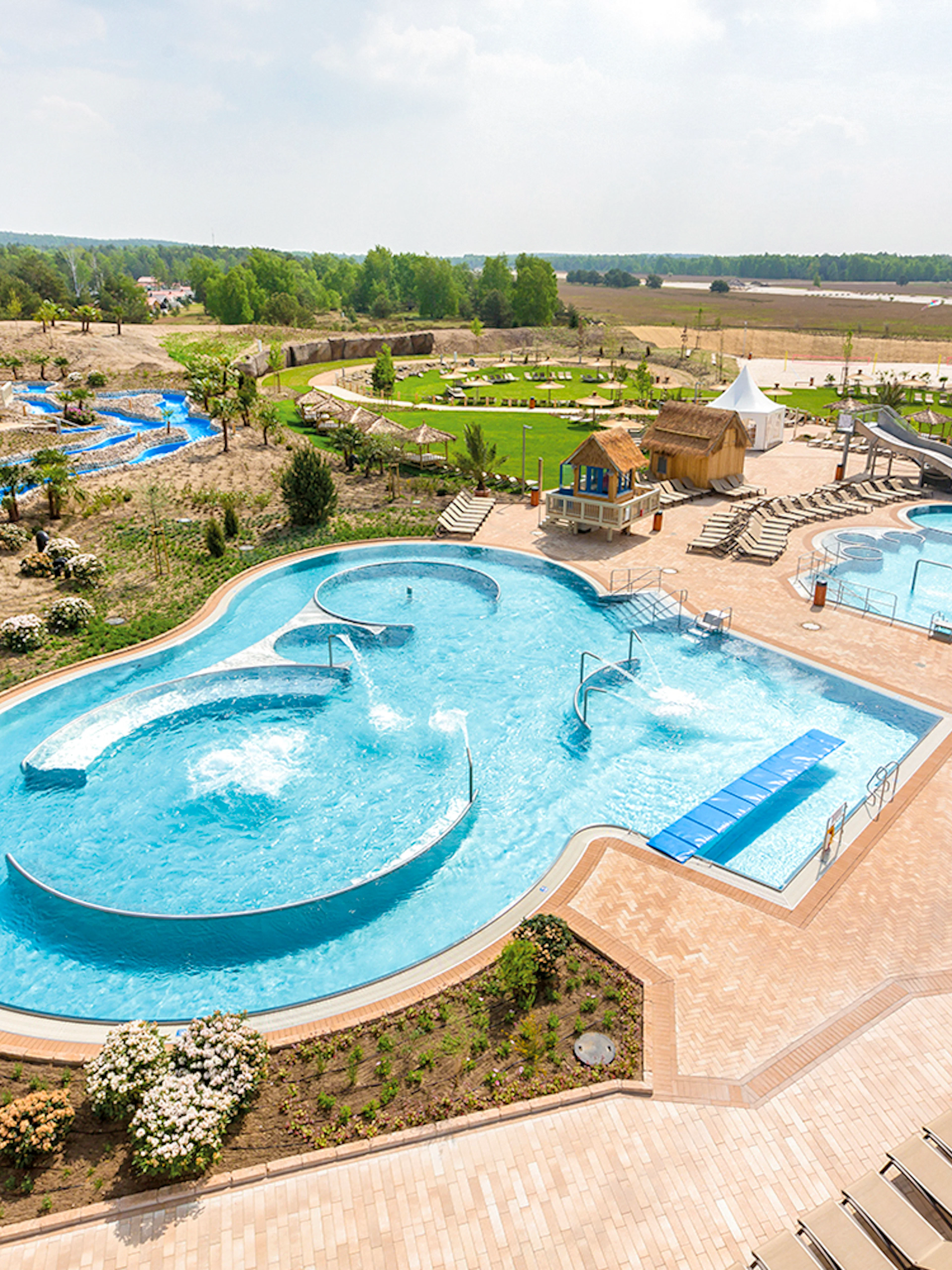 Outdoor pools and lazy river at Tropical Islands Resort, surrounded by greenery and lounge chairs.