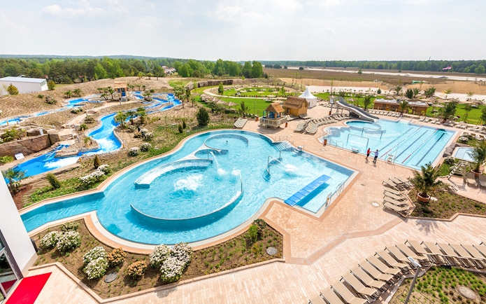 Outdoor pools and lazy river at Tropical Islands Resort, surrounded by greenery and lounge chairs.