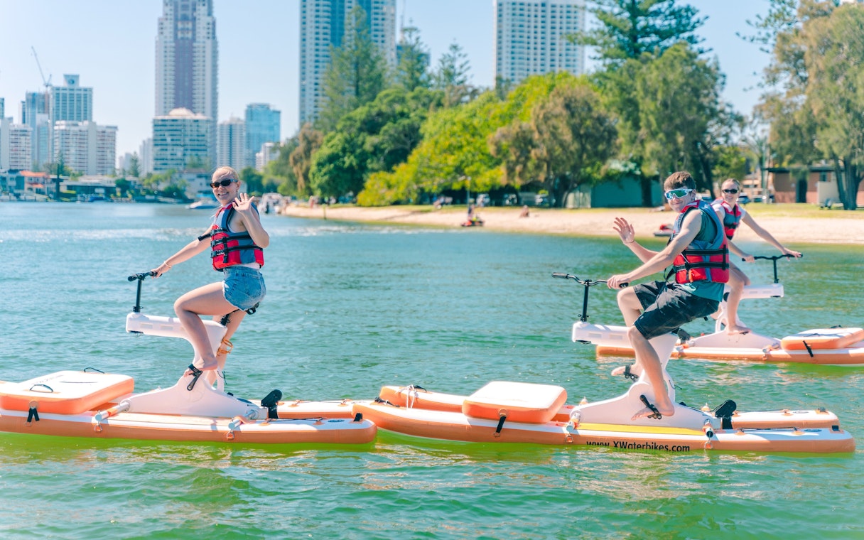 Tourists riding waterbikes on the water with Gold Coast skyline in the background.