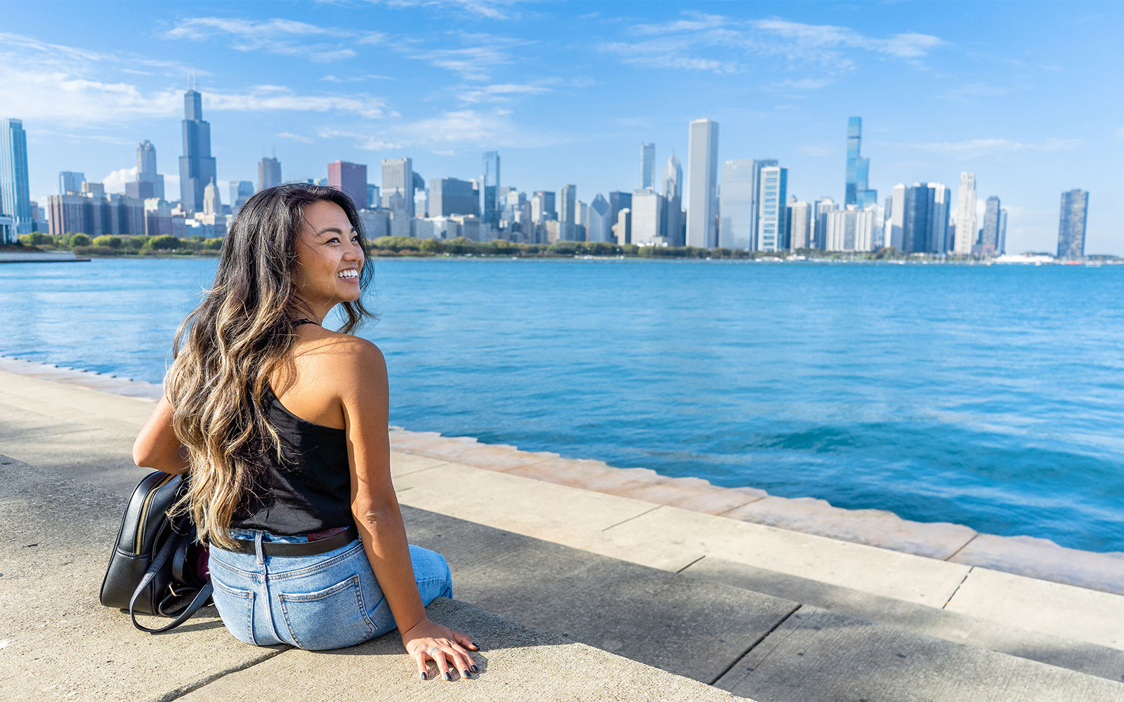 Person sitting by Lake Michigan with Chicago skyline in the background.