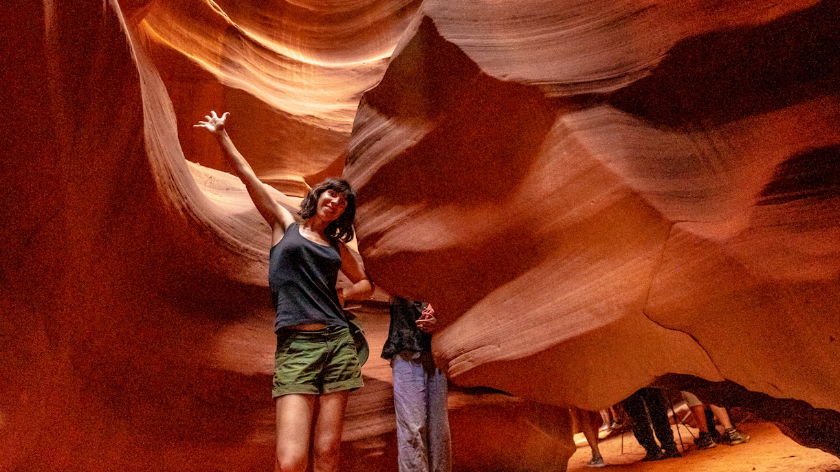 Young woman exploring Upper Antelope Canyon's sandstone formations.